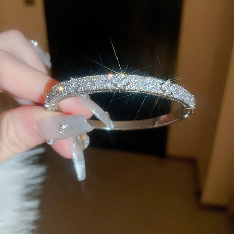 Hand holding a sparkling silver bracelet with a blurred background