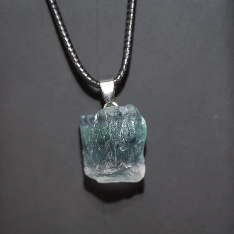 Necklace with a rough-cut gemstone pendant on a dark background