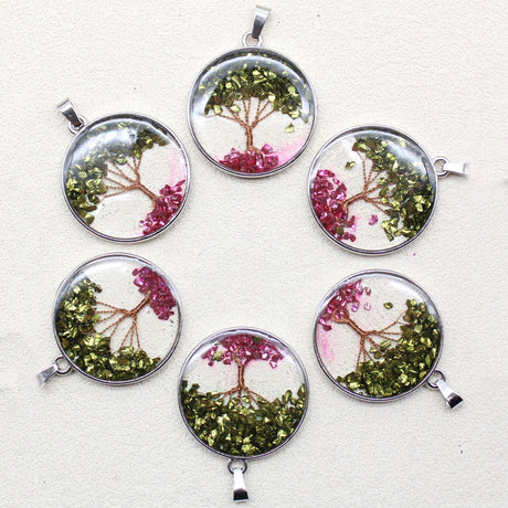Set of six round pendants with tree designs on a light background