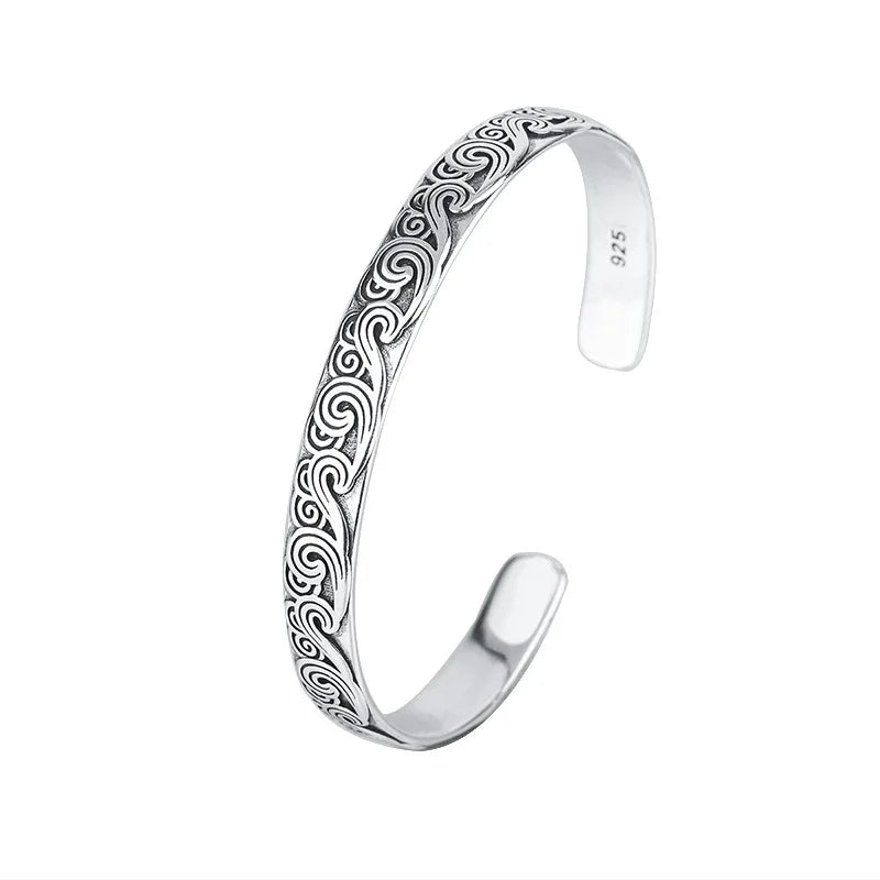 Silver bracelet with intricate patterns on a white background