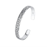 Silver bracelet with intricate patterns on a white background