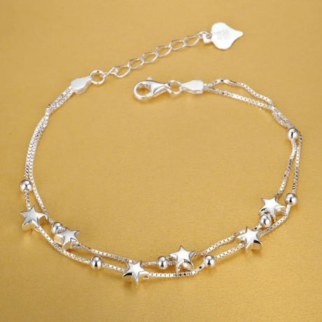 Silver anklet with star-shaped charms on a gold background
