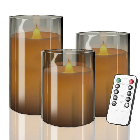 Set of three cylindrical glass candles with flameless candles inside and a remote control on a white background.