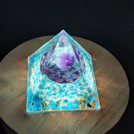 Pyramid-shaped crystal structure with glowing blue base on a wooden surface
