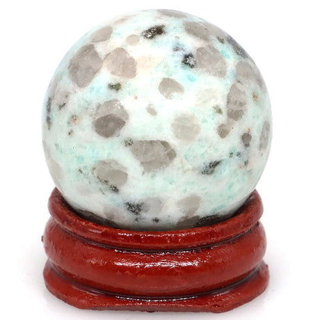 Speckled stone sphere on a red stand against a white background