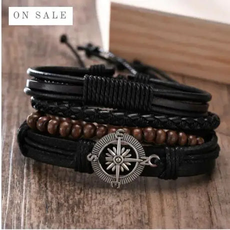 Stack of leather bracelets with a compass charm on a wooden surface, 'On Sale' label visible.