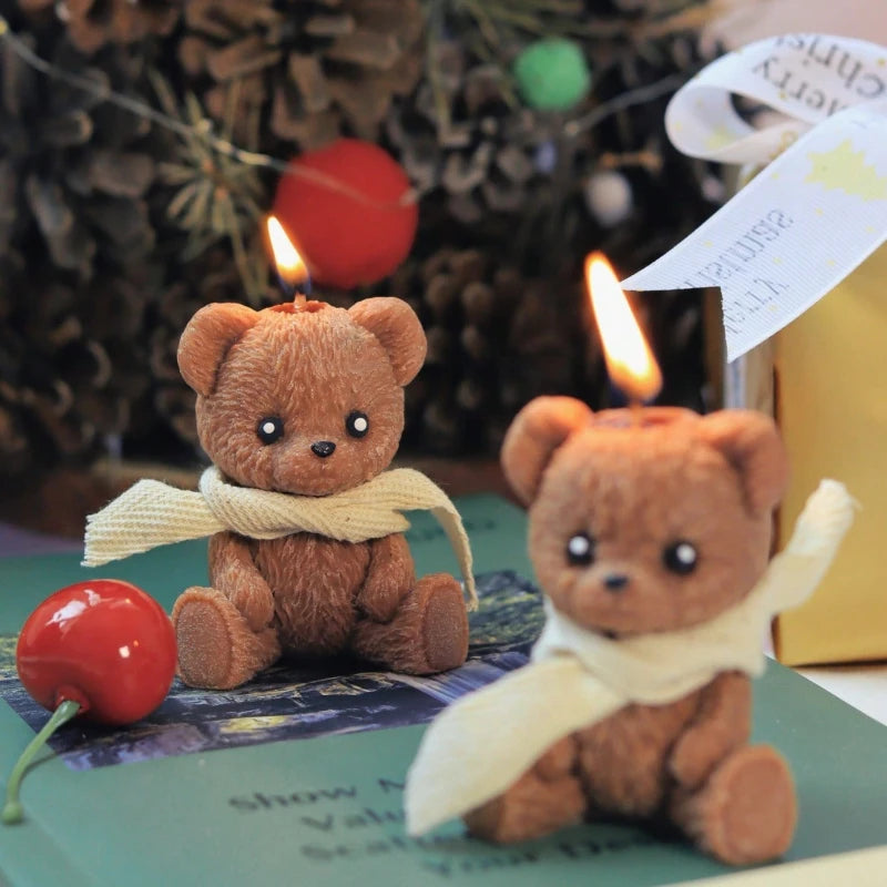 Two small teddy bears with scarves sitting on a surface with a blurred background.