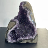 Amethyst geode on a reflective surface with a neutral background