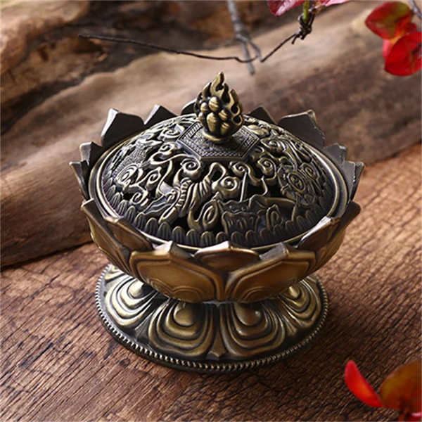 Decorative bronze incense burner on a wooden surface with floral elements.