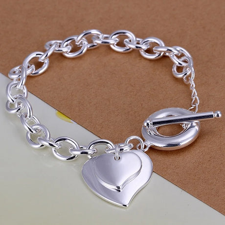 Silver chain bracelet with a heart-shaped charm on a brown background