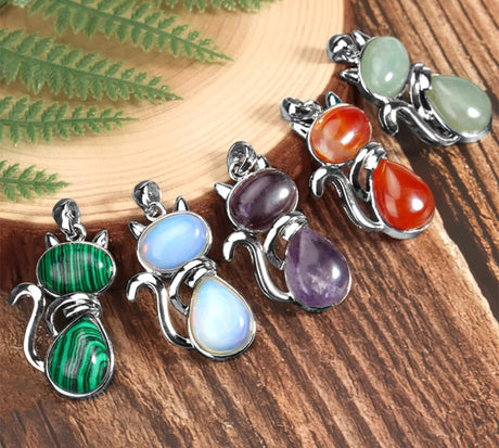 Set of colorful stone pendants on a wooden surface with green leaves.