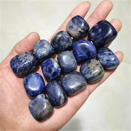 Hand holding a collection of blue stones against a white background