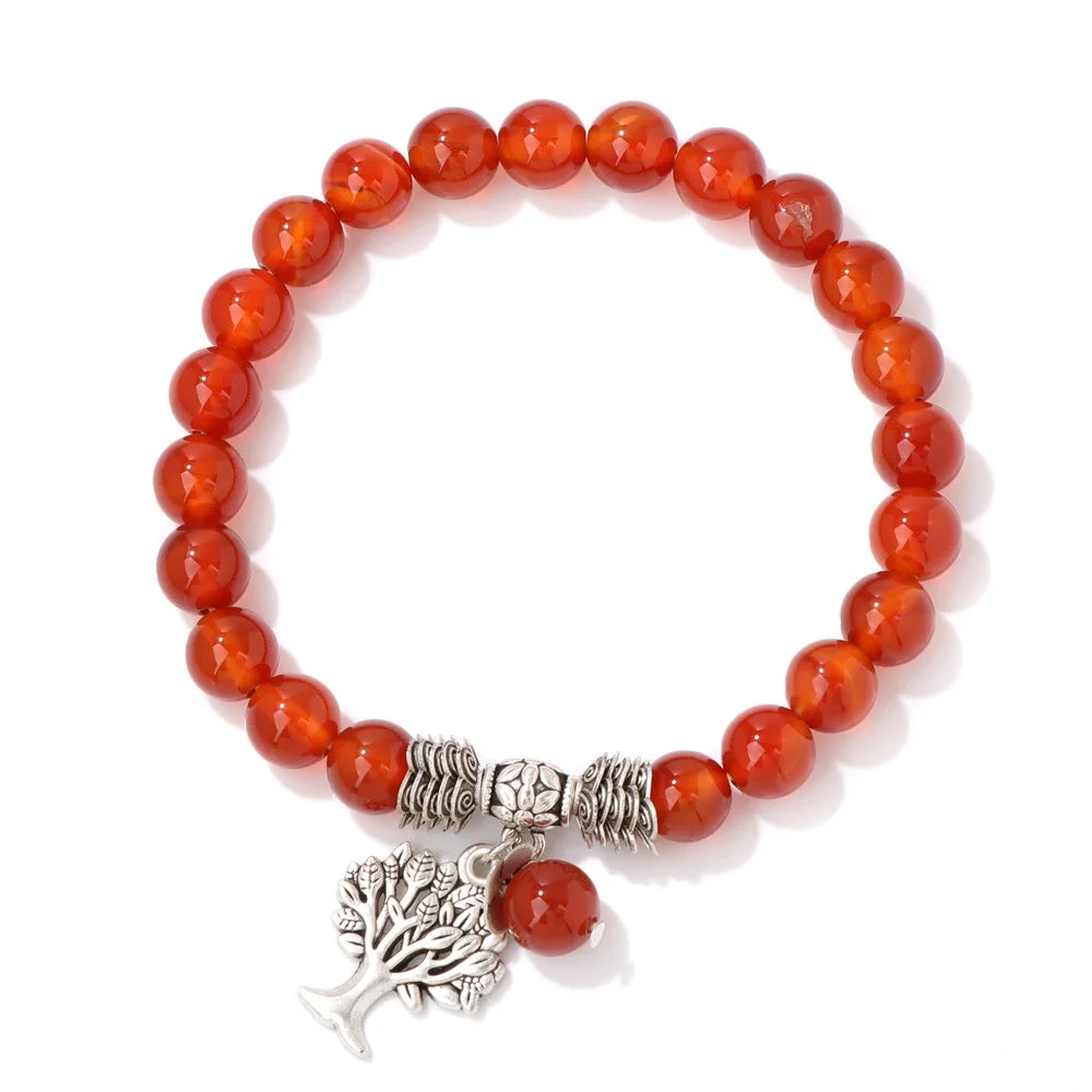 Bracelet with red beads and a silver tree charm on a white background