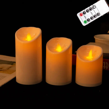 Three flameless candles with a remote control on a dark background