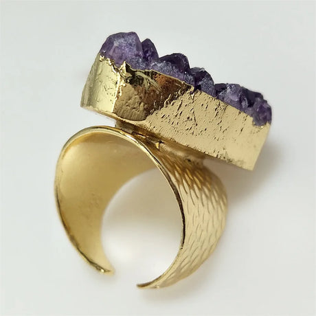 Gold ring with purple gemstone on a light gray background