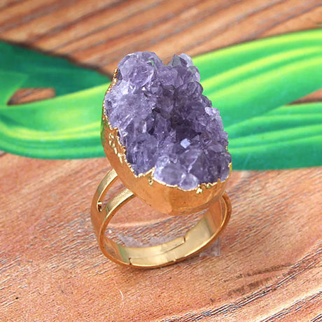 Gold ring with a purple geode stone on a wooden surface