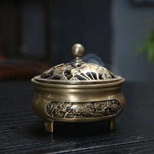 Bronze incense burner with intricate designs on a dark surface