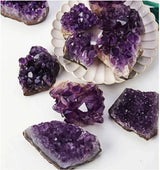 Amethyst crystals on a white surface with a decorative shell