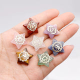 Hand holding star-shaped crystal pendants with various designs on a light background