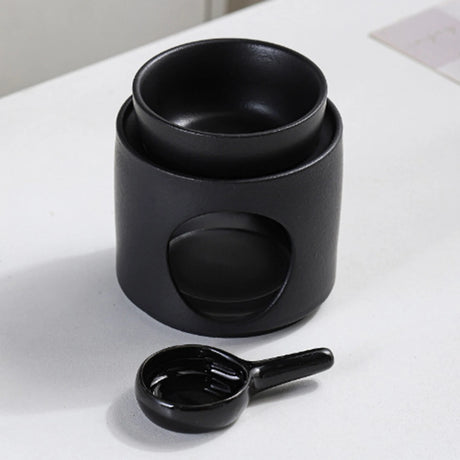 Set of black ceramic bowls and a measuring spoon on a white surface