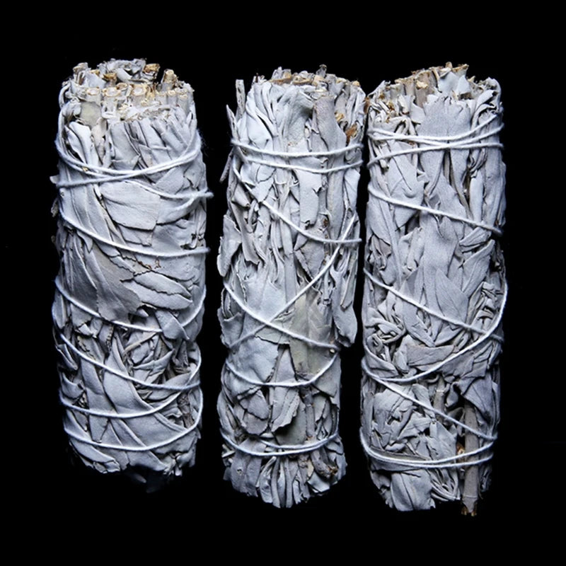 Three bundled sage smudge sticks on a black background