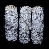 Three bundled sage smudge sticks on a black background