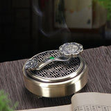 Decorative silver incense burner with intricate design on a wooden surface.