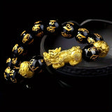 Bracelet with black beads and gold dragon charm on a dark background