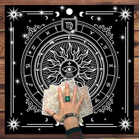 Hand holding tarot cards with a decorative astrological design on a wooden surface