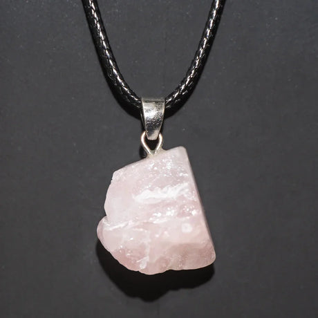 Pink stone pendant on a black cord against a dark background