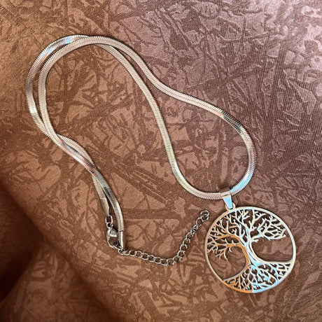 Silver necklace with a tree of life pendant on a textured brown fabric background