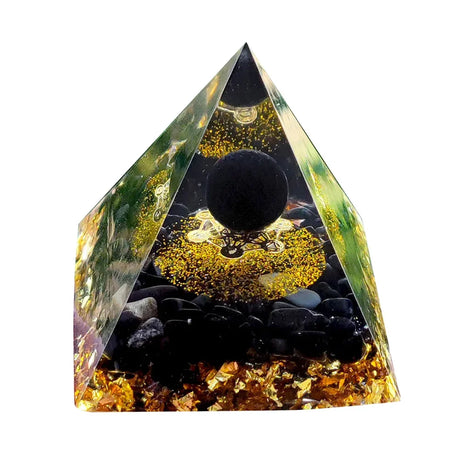 Pyramid-shaped crystal with black sphere and stones inside on a white background