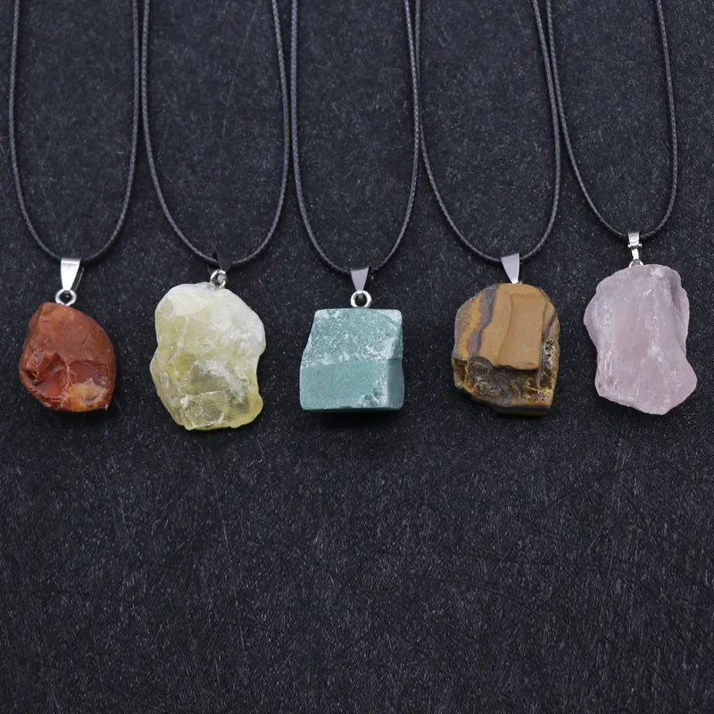Five stone pendants on black cords against a dark background