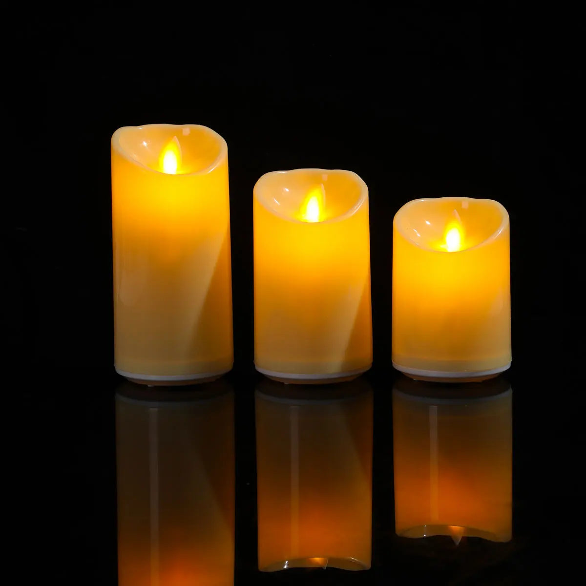 Three lit candles of different sizes on a reflective black surface with a dark background