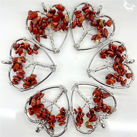 Five red stone pendants in silver heart frames on a white background