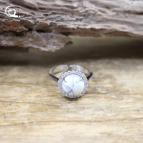 Silver ring with a white stone on a wooden surface