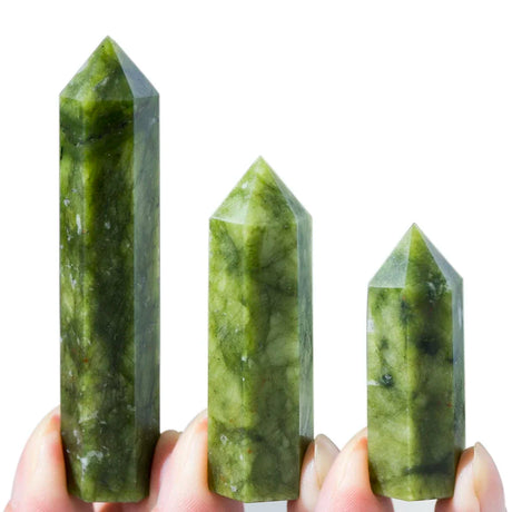 Three green crystal points held by a hand against a white background