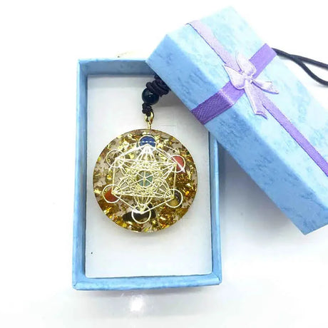 Decorative pendant in a blue box with a purple ribbon on a white background