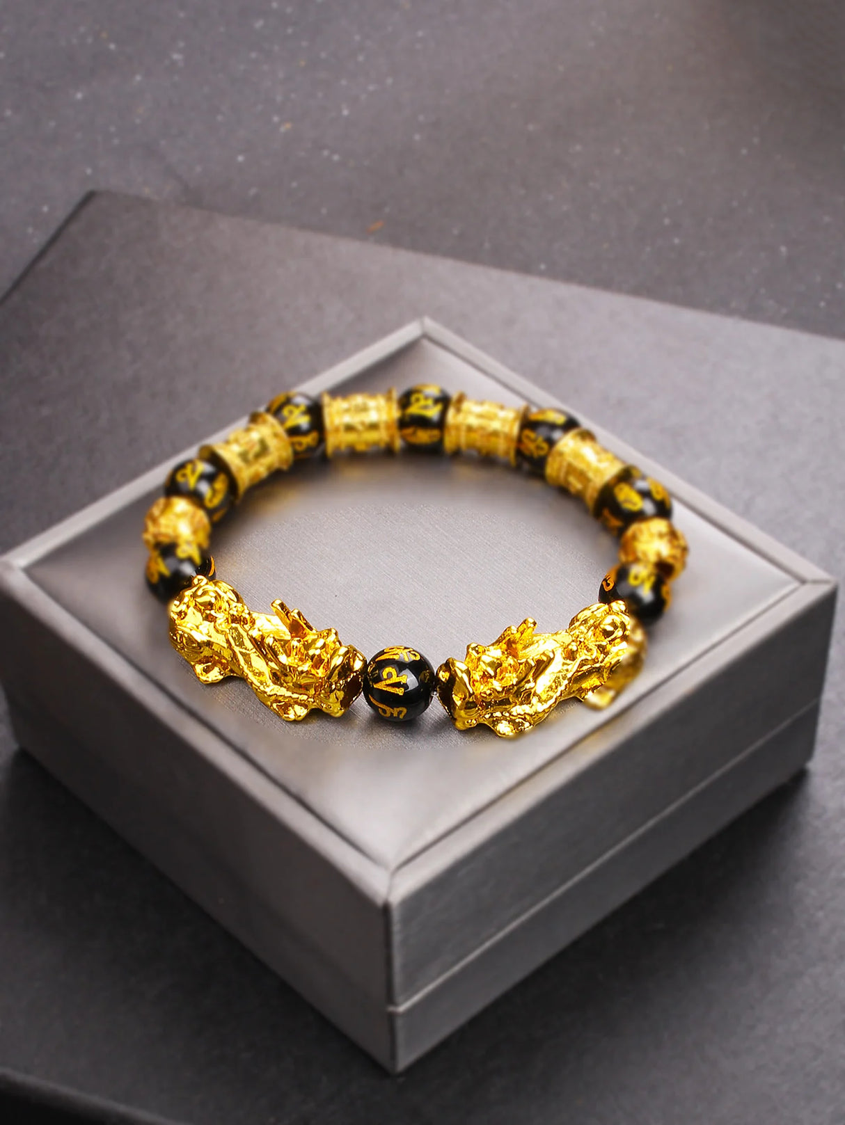 Gold and black beaded bracelet on a gray box