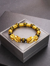 Gold and black beaded bracelet on a gray box