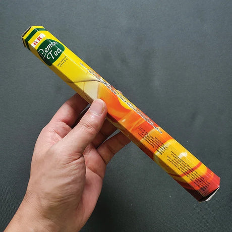 Hand holding a colorful cylindrical product with a brand label against a dark background