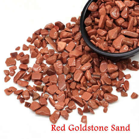 Red goldstone sand with a black bowl on a white background