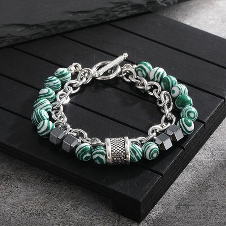 Bracelet with green and white marbled beads and silver chain on a dark wooden surface
