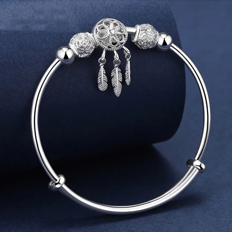 Silver bracelet with decorative beads and feathers on a dark blue background