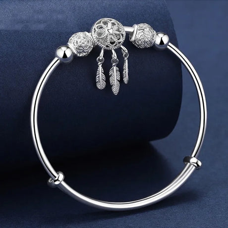 Silver bracelet with decorative beads and feathers on a dark blue background