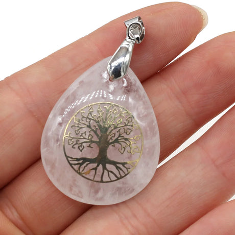 Teardrop-shaped pendant with tree of life design held in a hand