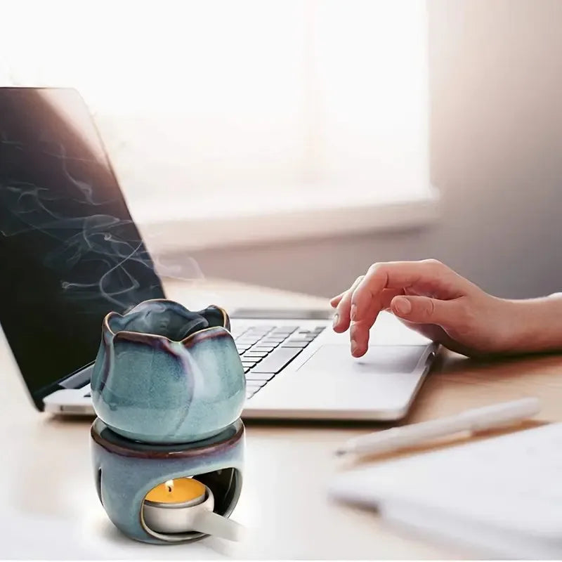 Ceramic diffuser with a candle on a desk next to a laptop