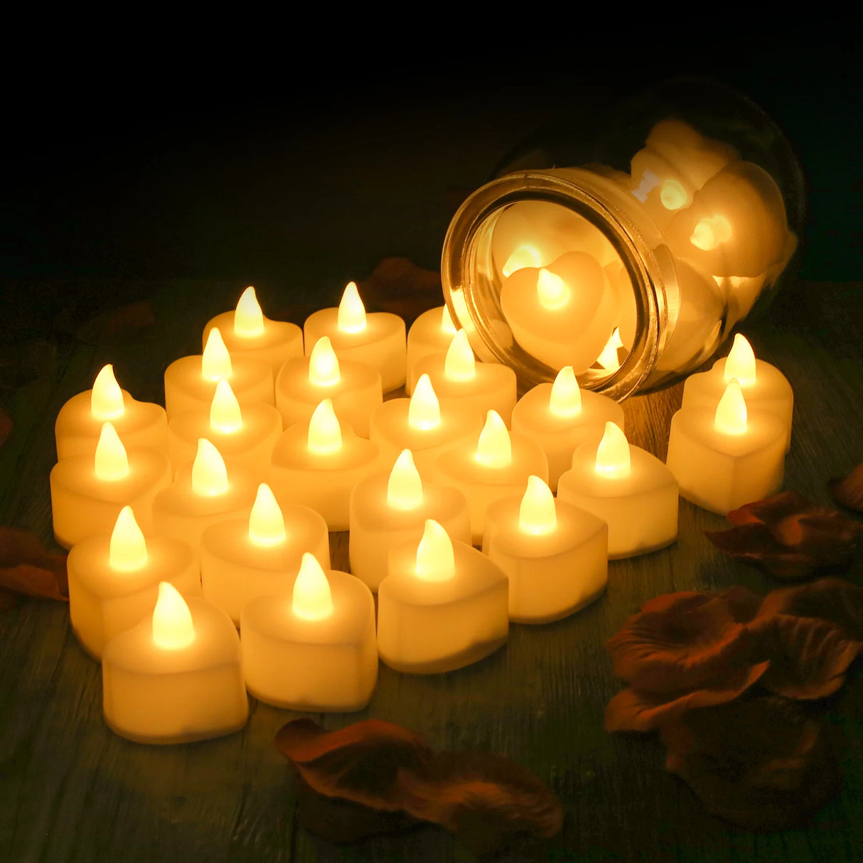 Set of small lit candles on a dark surface with a jar in the background