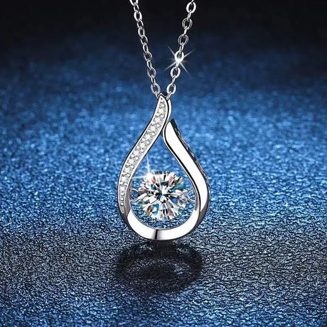 Silver teardrop-shaped pendant with a central gemstone on a dark blue textured background