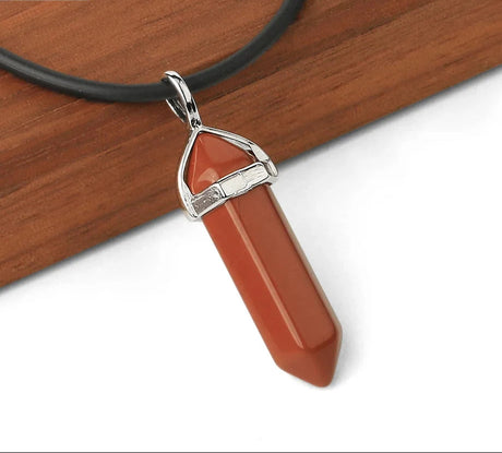 Red crystal pendant with silver top on a black cord against a wooden background